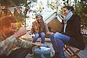 Happy friends playing cards at campsite