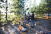 Friends drinking wine at sunny campsite in woods