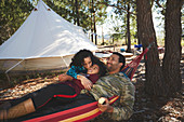 Family relaxing in hammock at campsite in woods