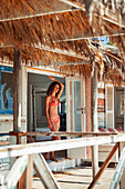 Serene young woman standing in beach hut patio doorway
