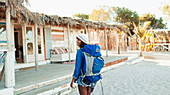 Young female backpacker arriving at beach hut