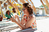 Carefree woman drinking cocktail at beach bar