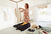 Woman unpacking suitcase in beach hut bedroom