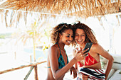 Happy young women friends using smart phone
