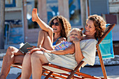 Playful, multi-generation women relaxing on beach