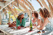 Women friends drinking cocktail and beer and beach bar