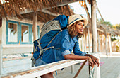 Happy young female backpacker on beach hut patio