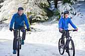 Couple mountain biking in snowy woods
