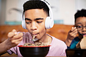 Teenage boy with headphones eating