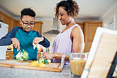 Mother and son cooking, cutting vegetables