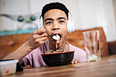 Portrait teenage boy eating at coffee table