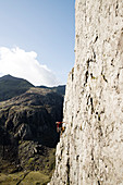 Male rock climber scaling large rock face