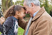 Grandfather and granddaughter on swing at playground