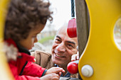Smiling grandfather playing with grandson at playground