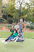 Grandparents and grandchildren playing on tire swing