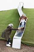 Grandparents with granddaughter on playground slide