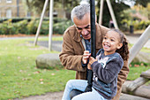 Happy grandfather and granddaughter playing at playground