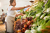Woman working, arranging produce at farmer's market