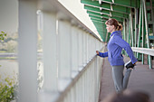 Young female runner stretching leg at urban railing