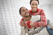 Portrait couple in Christmas sweaters piggybacking