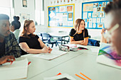 Students talking and studying at table in classroom