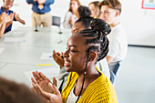 Smiling high school girl student clapping in classroom