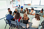 Students talking in debate class at table in classroom