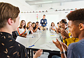 Students and teacher clapping for student in debate class