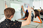 High school boy student with hand raised during lesson