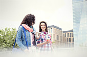 Young women friends with coffee walking in city