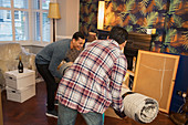 Men moving rug into living room of new house