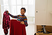 Woman unpacking clothing from moving box in bedroom