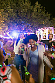 Happy friends dancing and drinking at garden party