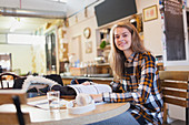 Portrait female college student studying at cafe table