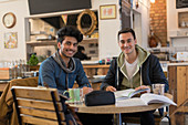 Portrait male college students studying at cafe table