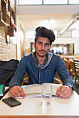 Portrait young male college student studying at cafe table