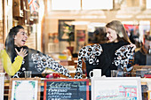 Happy women friends with matching sweaters in cafe window