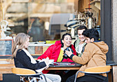Students with digital camera at sidewalk cafe