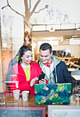 Young couple using smart phone at cafe window