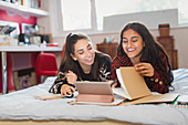 Teenage girl friends studying doing homework on bed