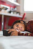 Teenage girl using smart phone playing on bed
