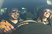 Happy young couple wearing sunglasses in car