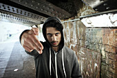 Portrait tough man gesturing finger gun in urban tunnel