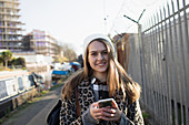 Portrait young woman with smart phone on urban sidewalk