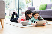 Girls watching movie with tablet on living room floor
