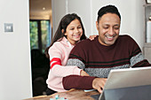 Smiling father and daughter using digital tablet at table