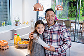 Portrait happy father and daughter hugging in kitchen