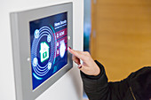 Woman setting smart home security alarm at touch screen