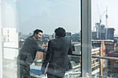 Businessmen talking on sunny, urban balcony