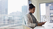 Businesswoman using smart phone in urban conference room